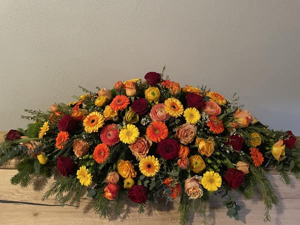 Farbenfrohes Sargbukett in Gelb-, Orange- und Rottönen